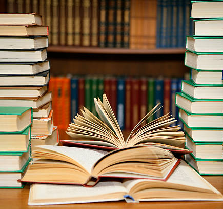 Tumpukan buku motivasi terbaik di atas meja dengan latar belakang perpustakaan